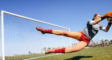 woman soccer goalie stopping a goal attempt