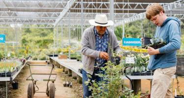 Teacher and student tending to greenhouse plants