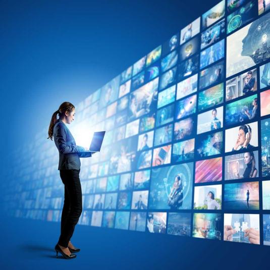 A woman standing in front of a wall of screens playing videos