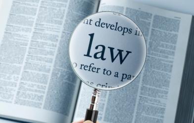 Picture of an open dictionary with the word "Law" enlarged with a magnifying glass