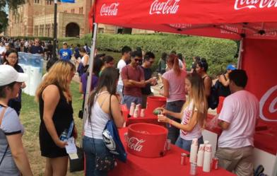 Students giving away Coke drinks at an outdoor event