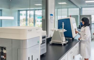 Woman in a lab using a piece of equipment on the table