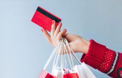 womans hand holding a credit card and shopping bags