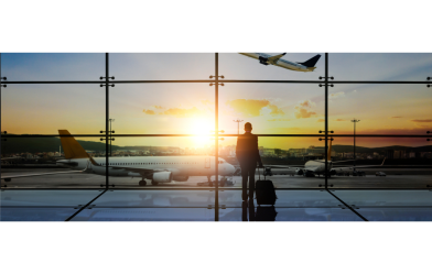 Traveler looking out airport window at departing plane