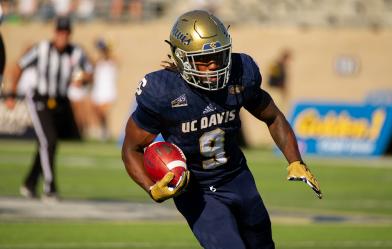 Football player carrying ball down field