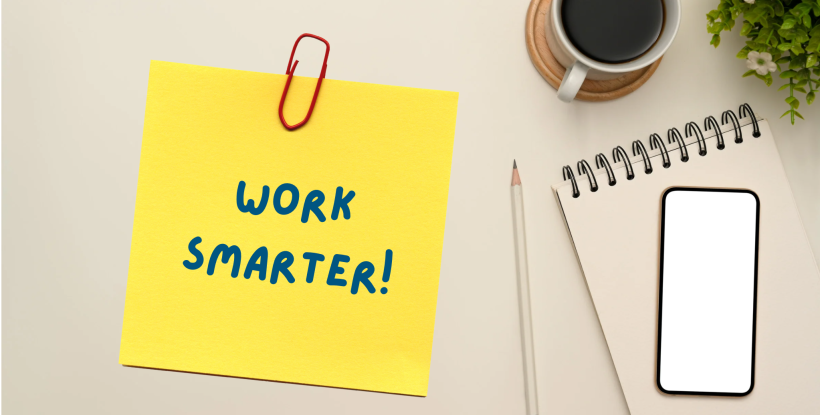 A desktop with a post-it note saying work smarter!
