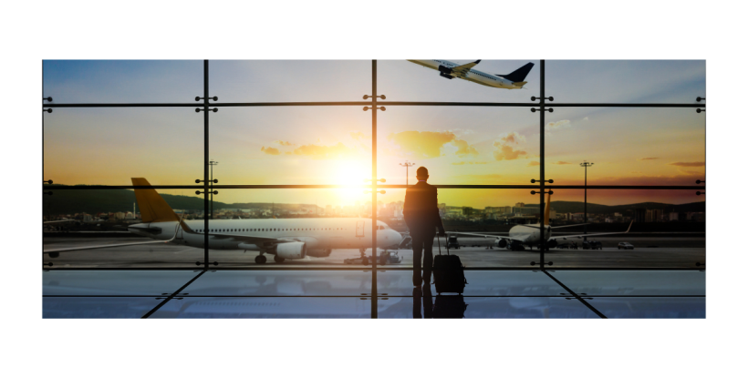 Traveler looking out airport window at departing plane