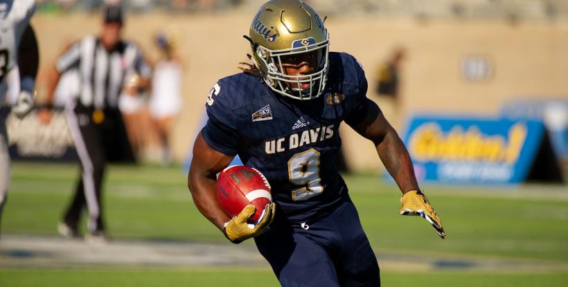 Football player carrying ball down field