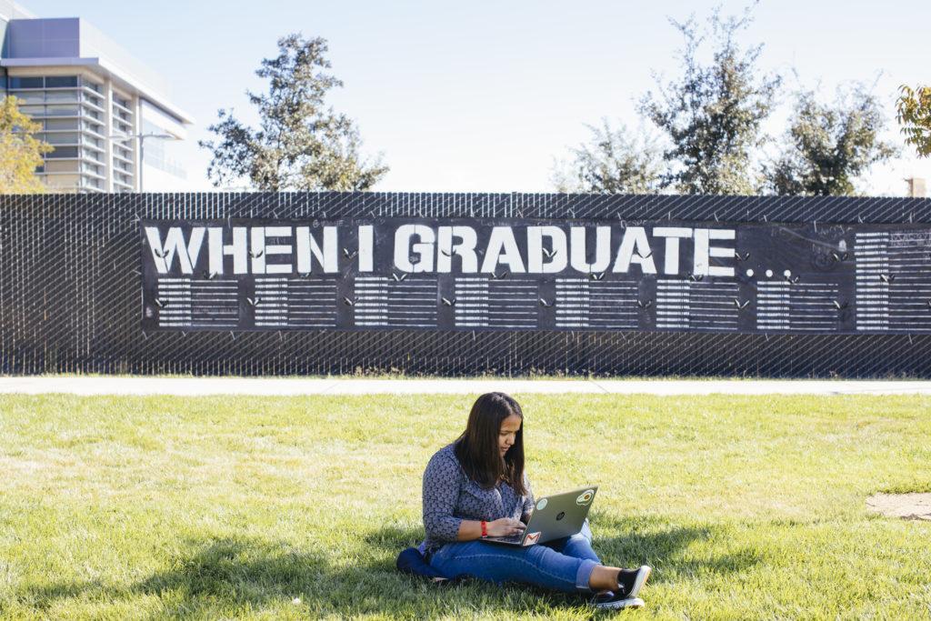 A student sitting on the grass with the words "When I graduate" above their head