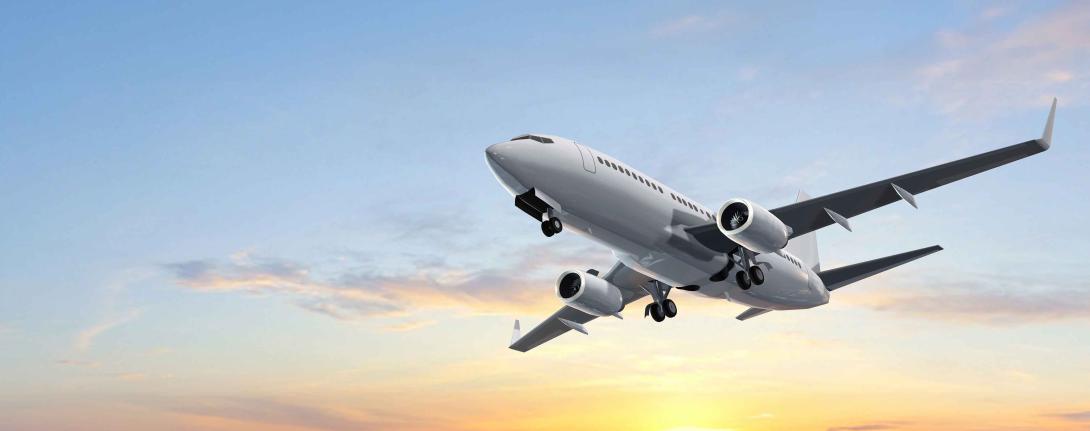 A commercial airplane taking off with a sunset behind it