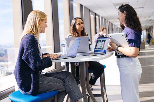 three women at a table with laptops