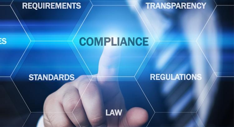 Abstract image showing a hand pressing a glass tile reading "compliance" -- other tiles read "Requirements" "Transparency" "Standards" "Regulations" and "Law"