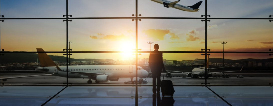 Traveler looking out airport window at departing plane