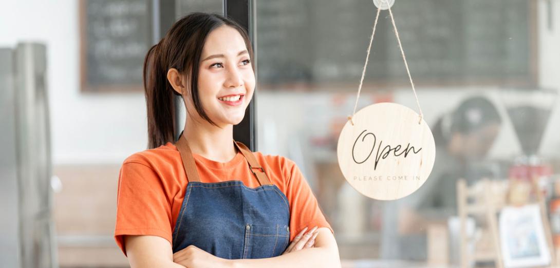 A female small business owner in front of her shop